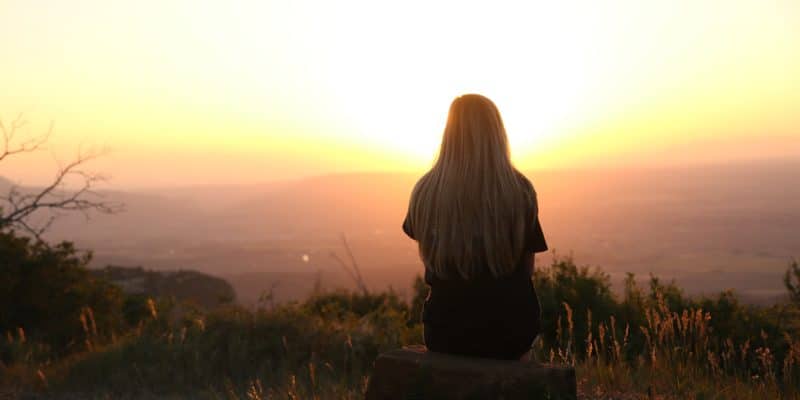 Ensomhet kvinne sitter med ryggen mot i solnedgang